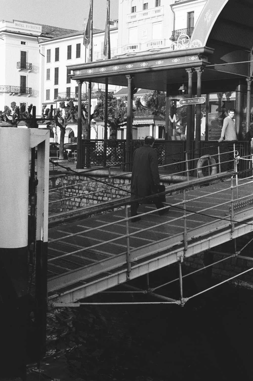 person walking on a bridge grey-scale photography