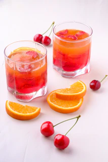 two orange and cherry drink in glasses