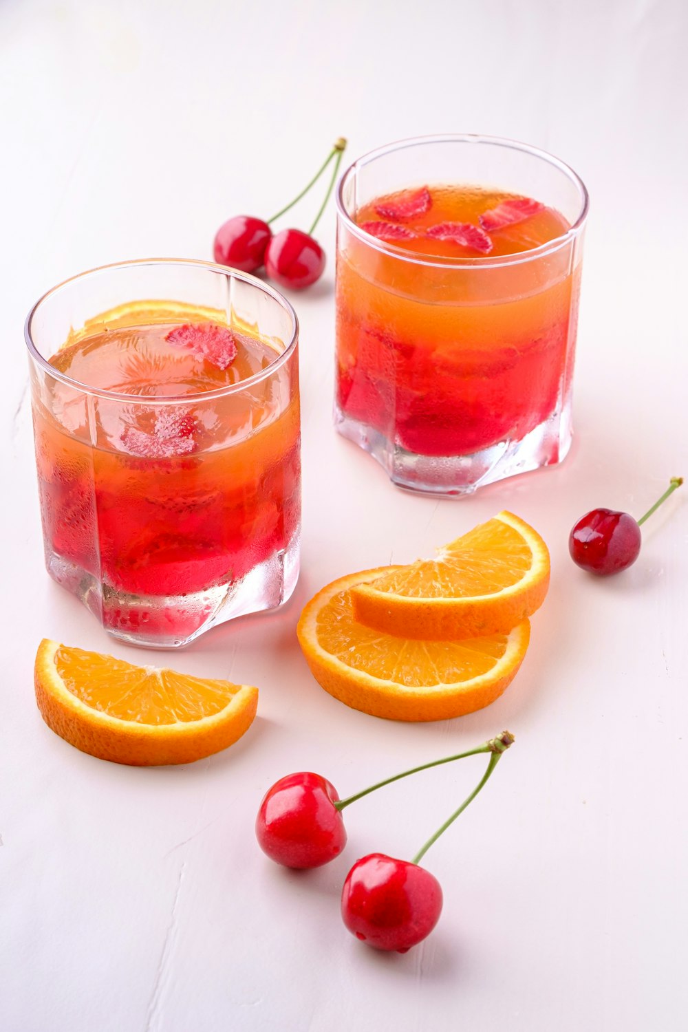 duas bebidas de laranja e cereja em copos