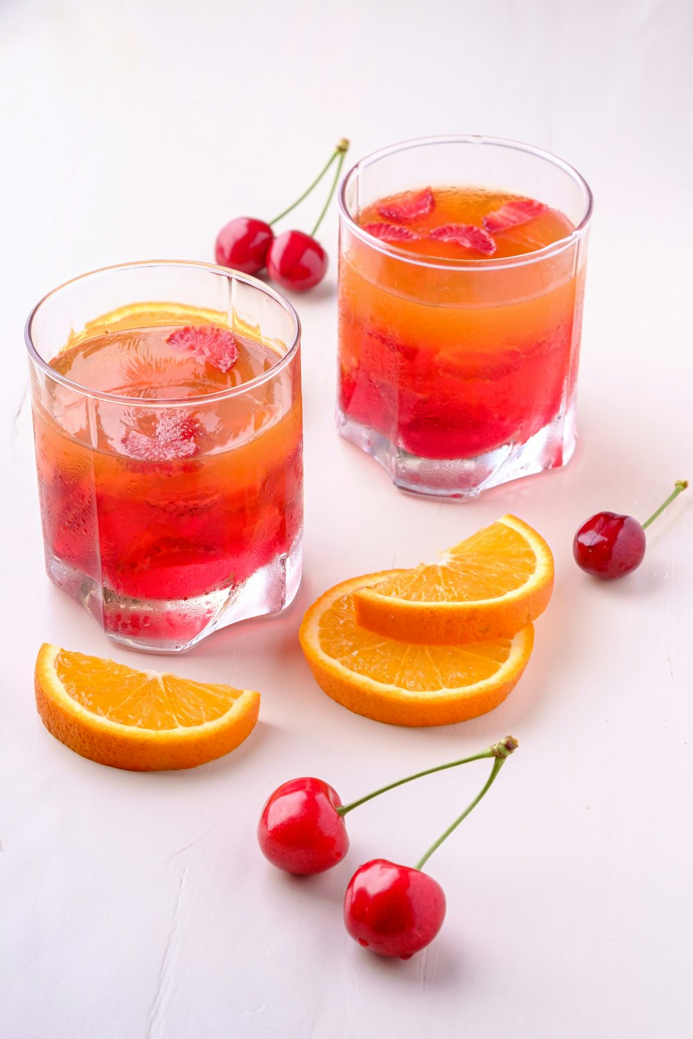 two orange and cherry drink in glasses