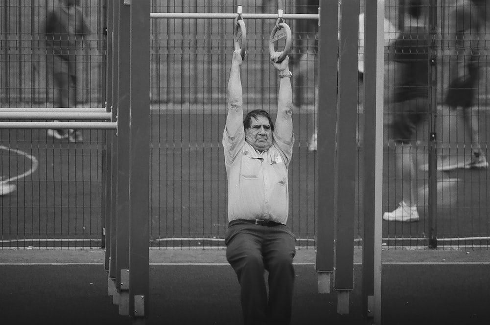 grey-scale photography of a men swinging on a loop close-up photography