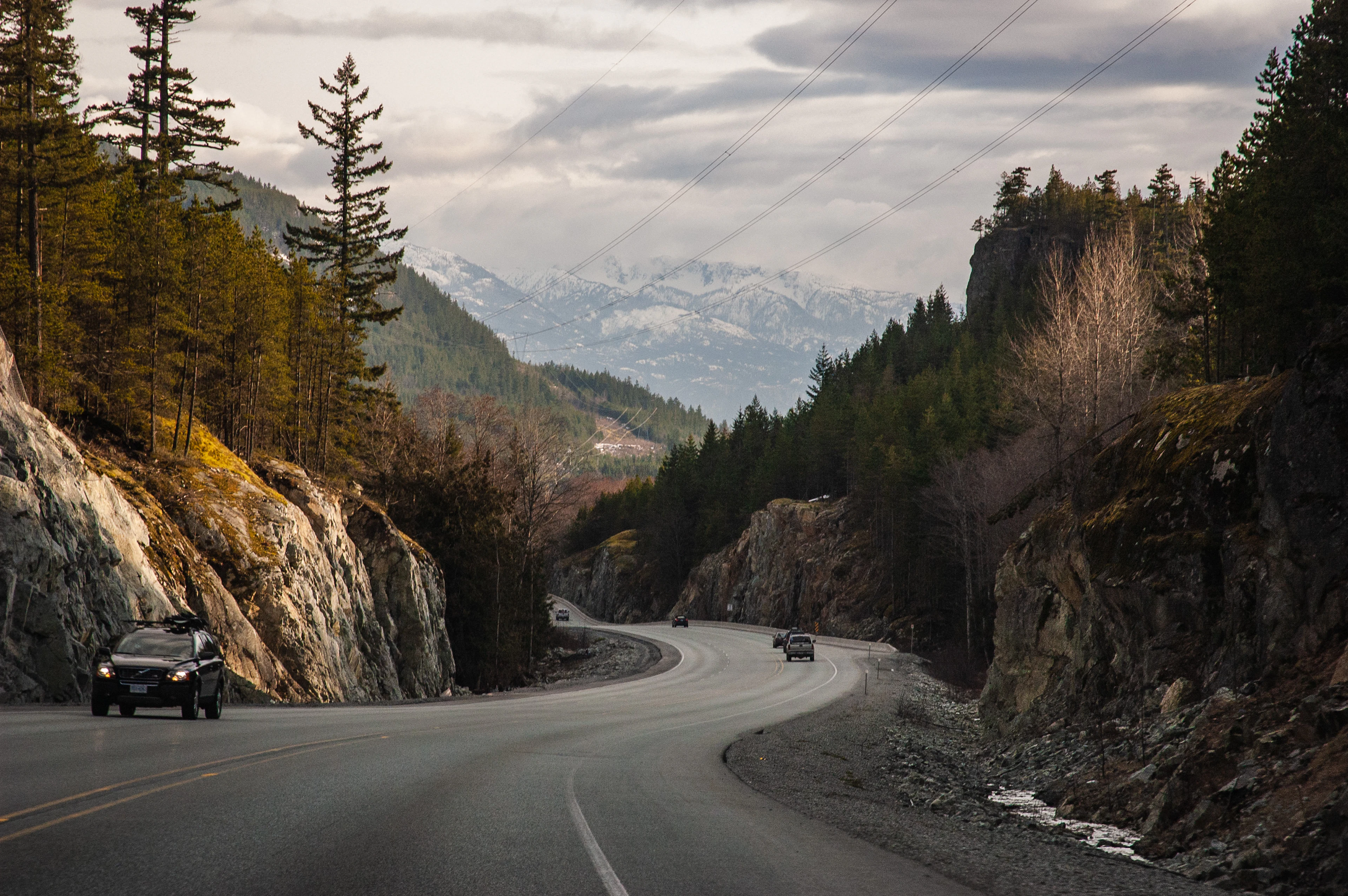 Des voitures roulent sur la Sea to Sky Highway, entre forêts et montagnes enneigées de Colombie-Britannique