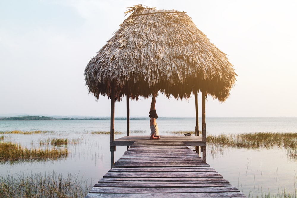 person inverting body on gray straw hat viewing calm sea