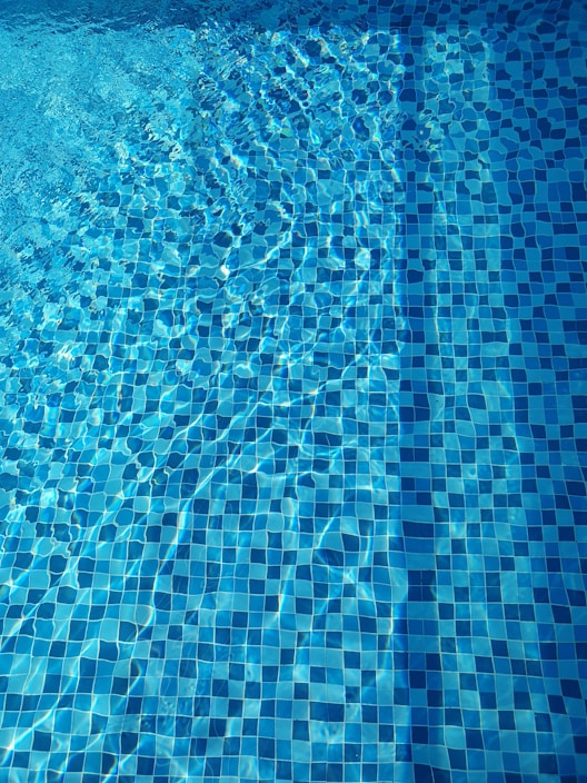 Close-up of a powerful pool pump set beside a crystal-clear swimming pool under bright sunlight