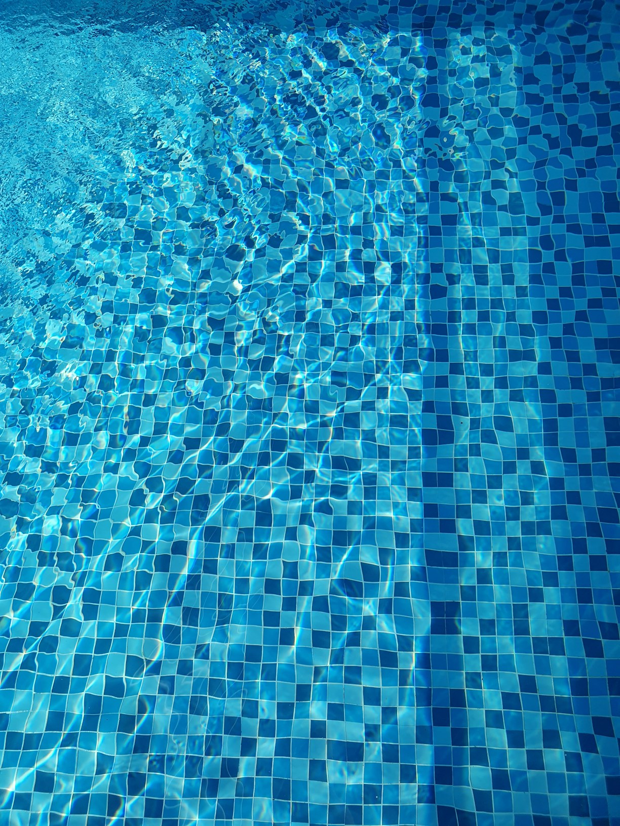 Close-up of a sparkling swimming pool with clear water and colorful RGB lights glowing underwater