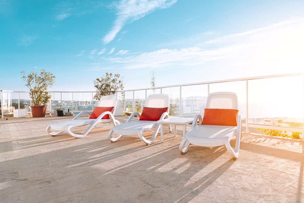 three white lawn chair with orange pillows