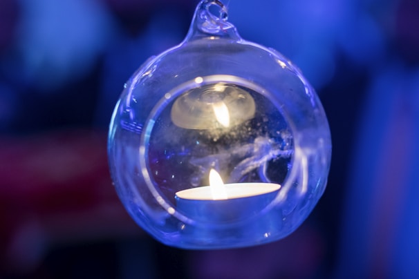 Close-up of a Serendilux candle with a glowing flame inside a minimalist glass container topped with bamboo lid.