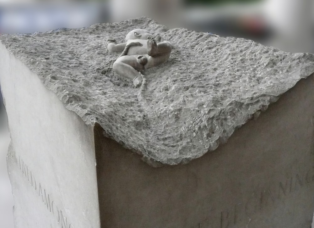 a small teddy bear laying on top of a cement block