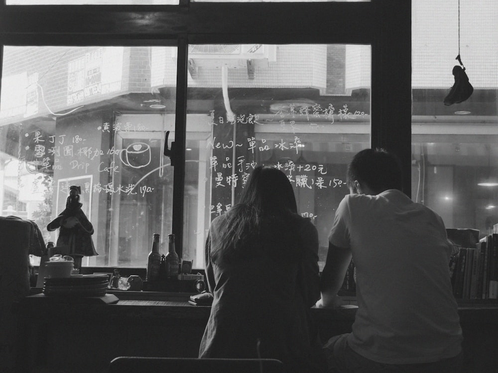 man and woman sitting near window