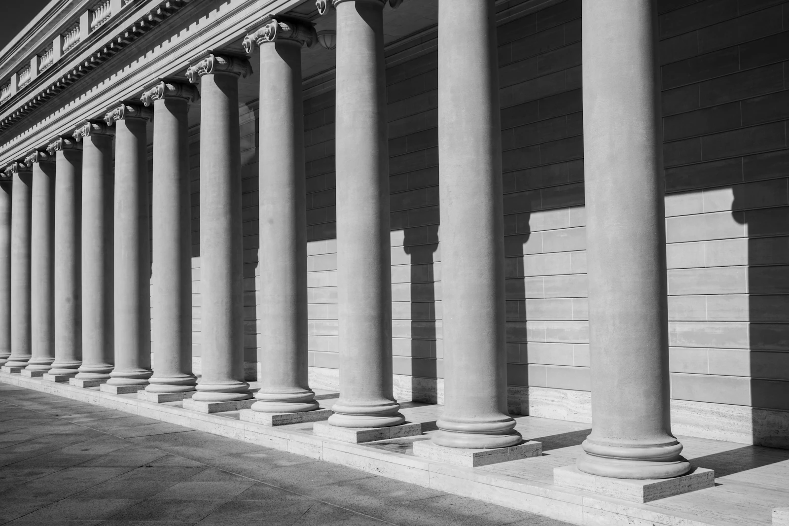 A long stone colonnade in raking light, in black and white