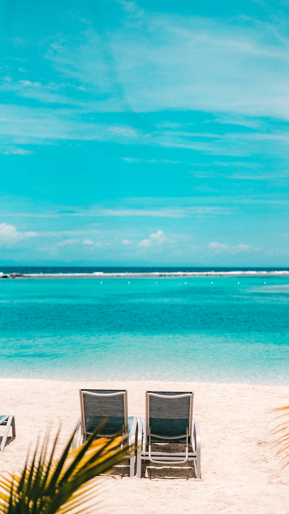 two black and gray lawn chairs on a beach