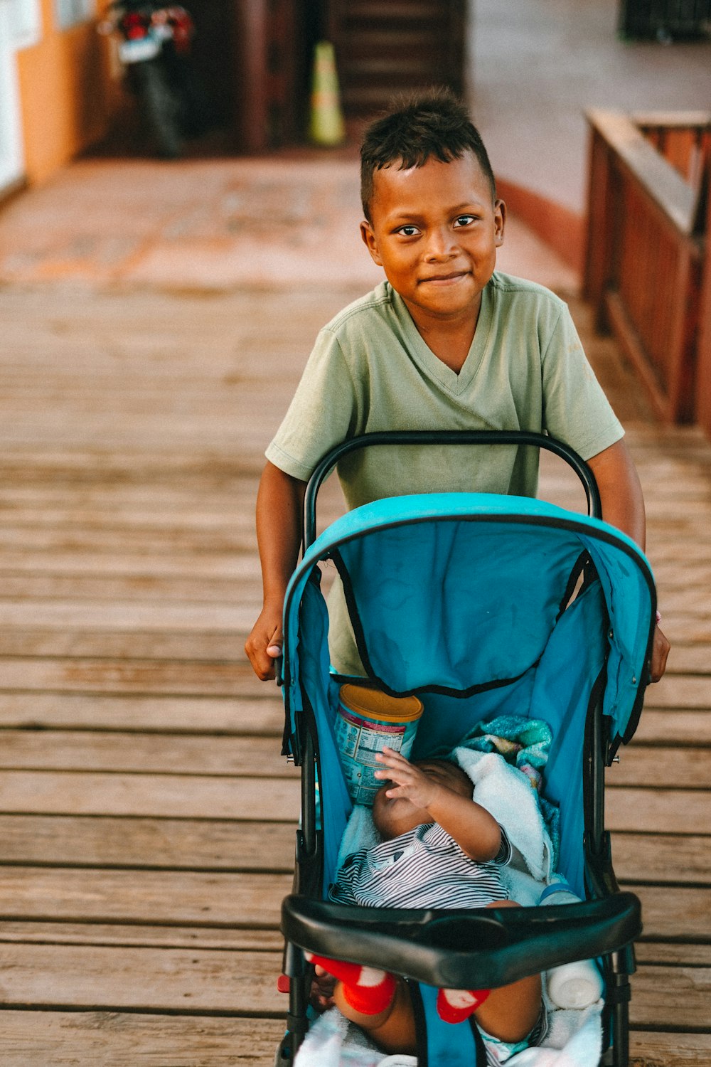 boy pushing stroller while smiling during daytime