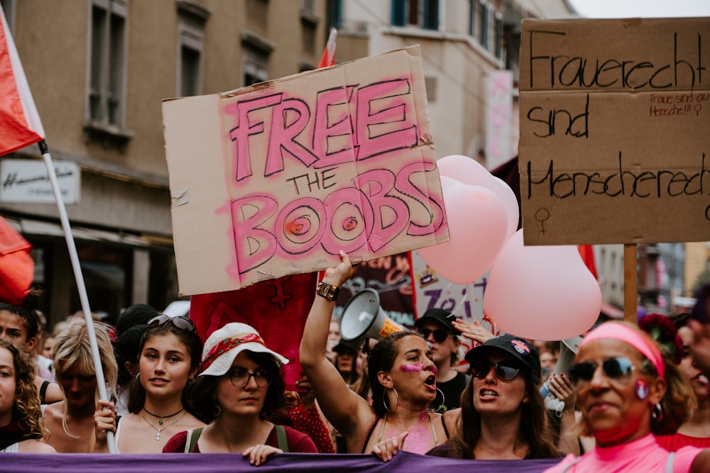 women rallying on street raising signs