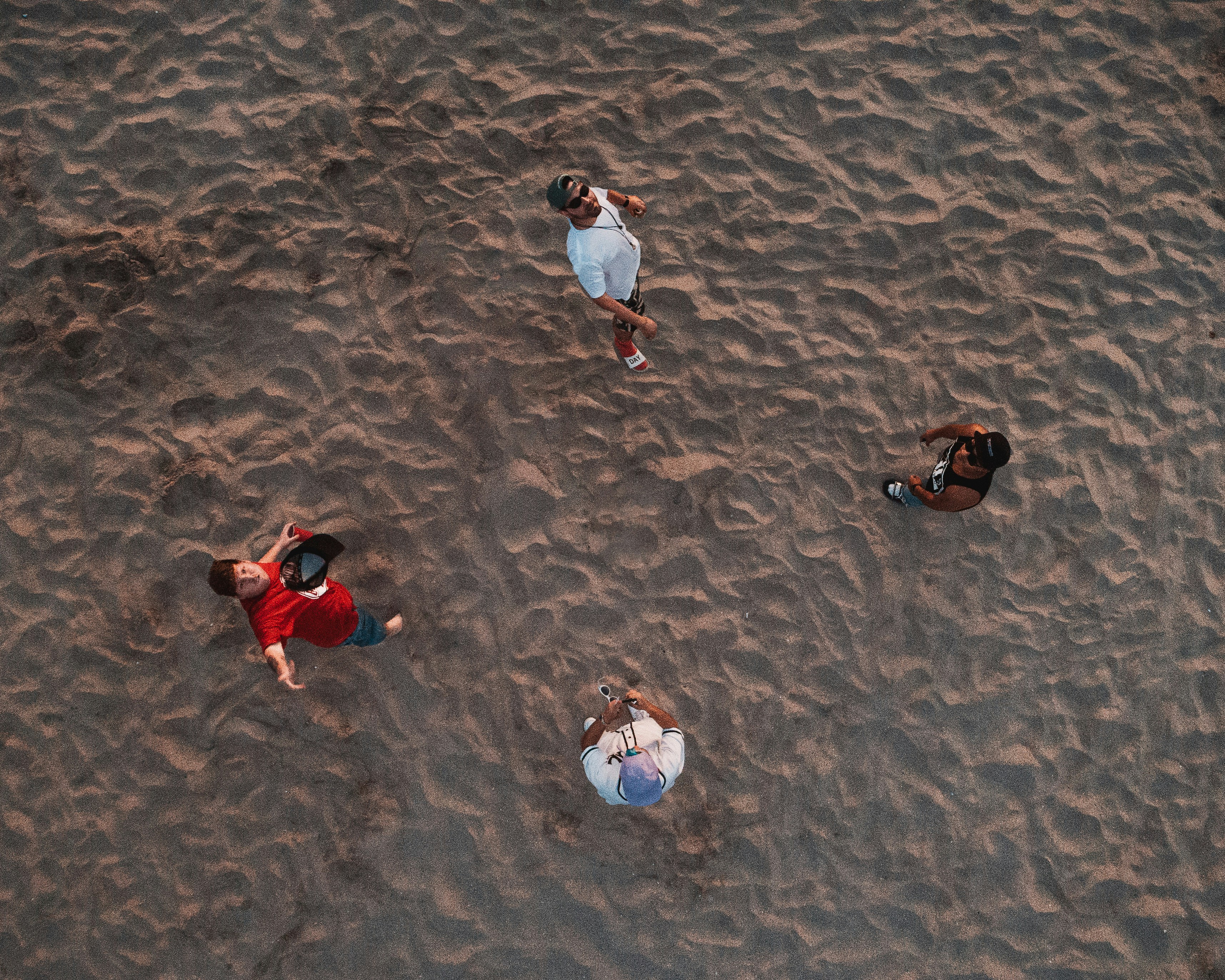 four person stand on beach sand