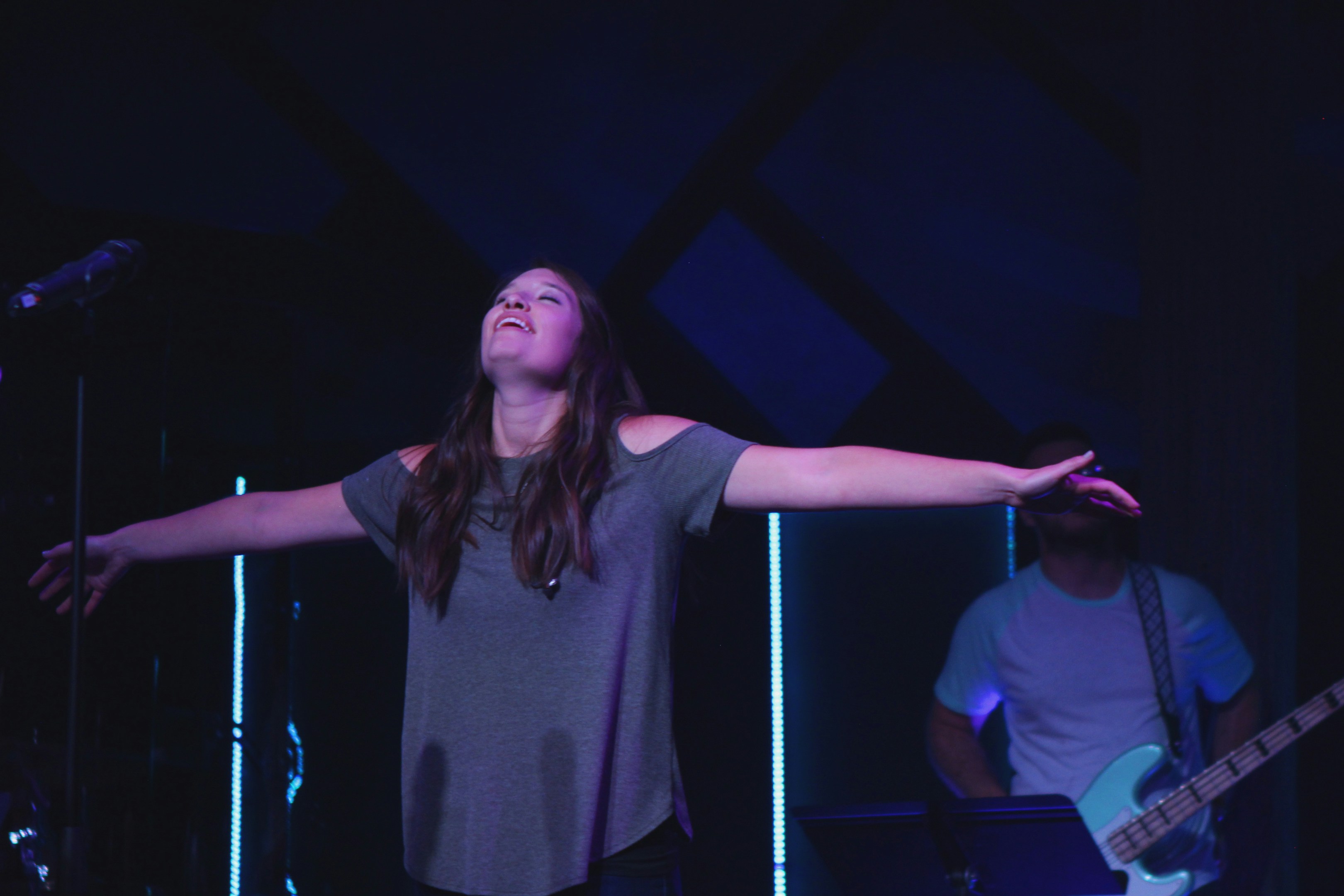 woman with hands raised on a dark stage