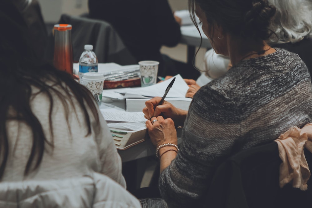 woman wearing grey shirt writing on white paper