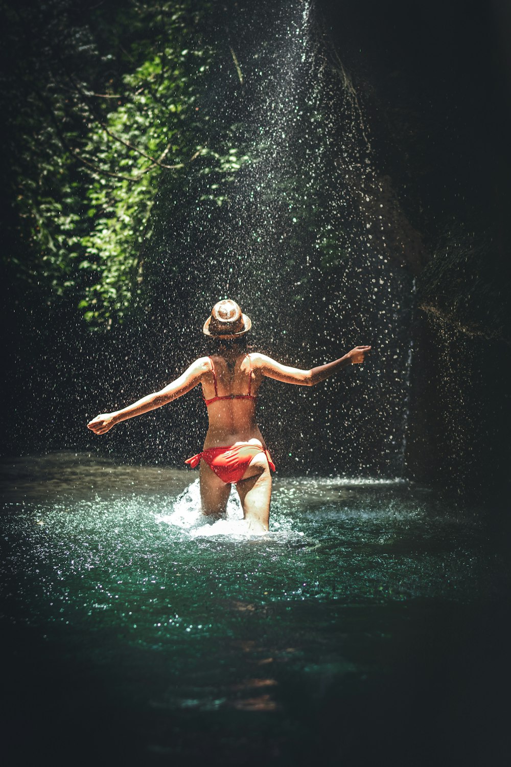 woman walking on body of water wearing red bikini