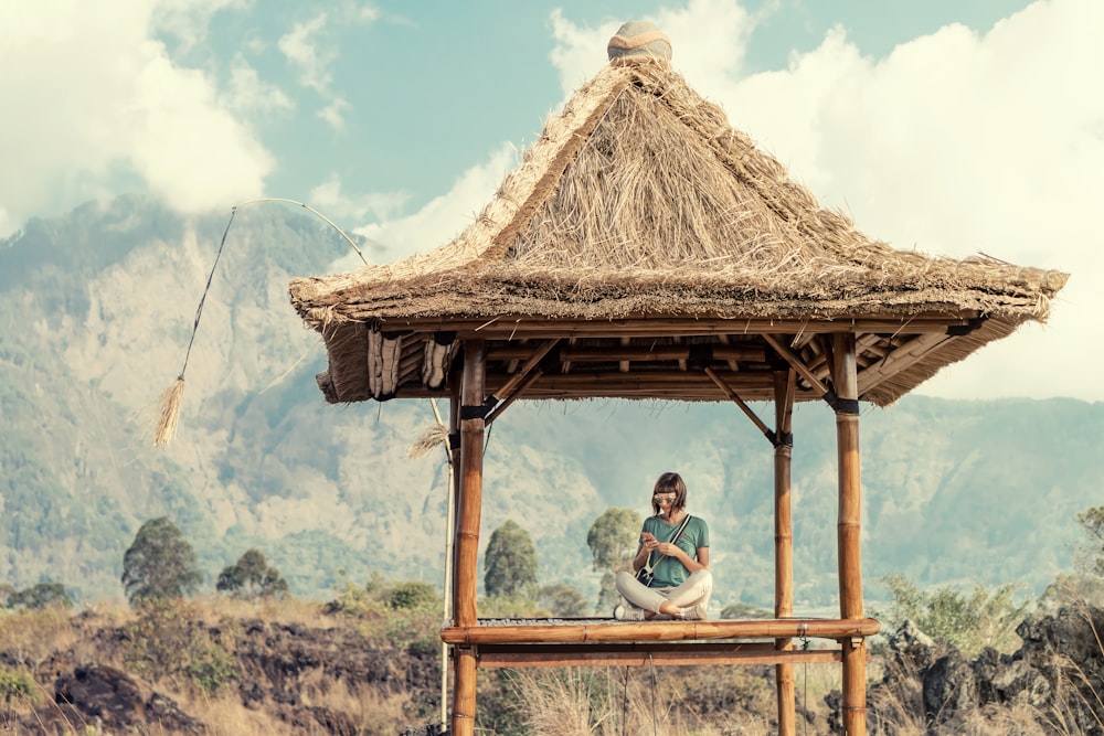 woman sitting in lotus position in floor of brown wooden hut