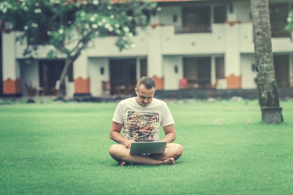 man sitting on ground while using smartphone