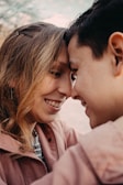 A couple is leaning their foreheads together, smiling warmly at each other, creating a tender and intimate moment.