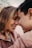 A couple is leaning their foreheads together, smiling warmly at each other, creating a tender and intimate moment.
