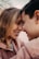 A couple is leaning their foreheads together, smiling warmly at each other, creating a tender and intimate moment.