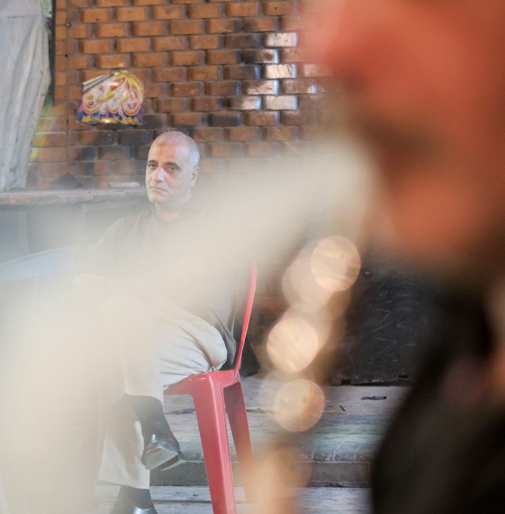 man sitting on red chair with cross legs