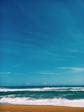 A scenic view of a tranquil beach with gentle waves and clear skies.