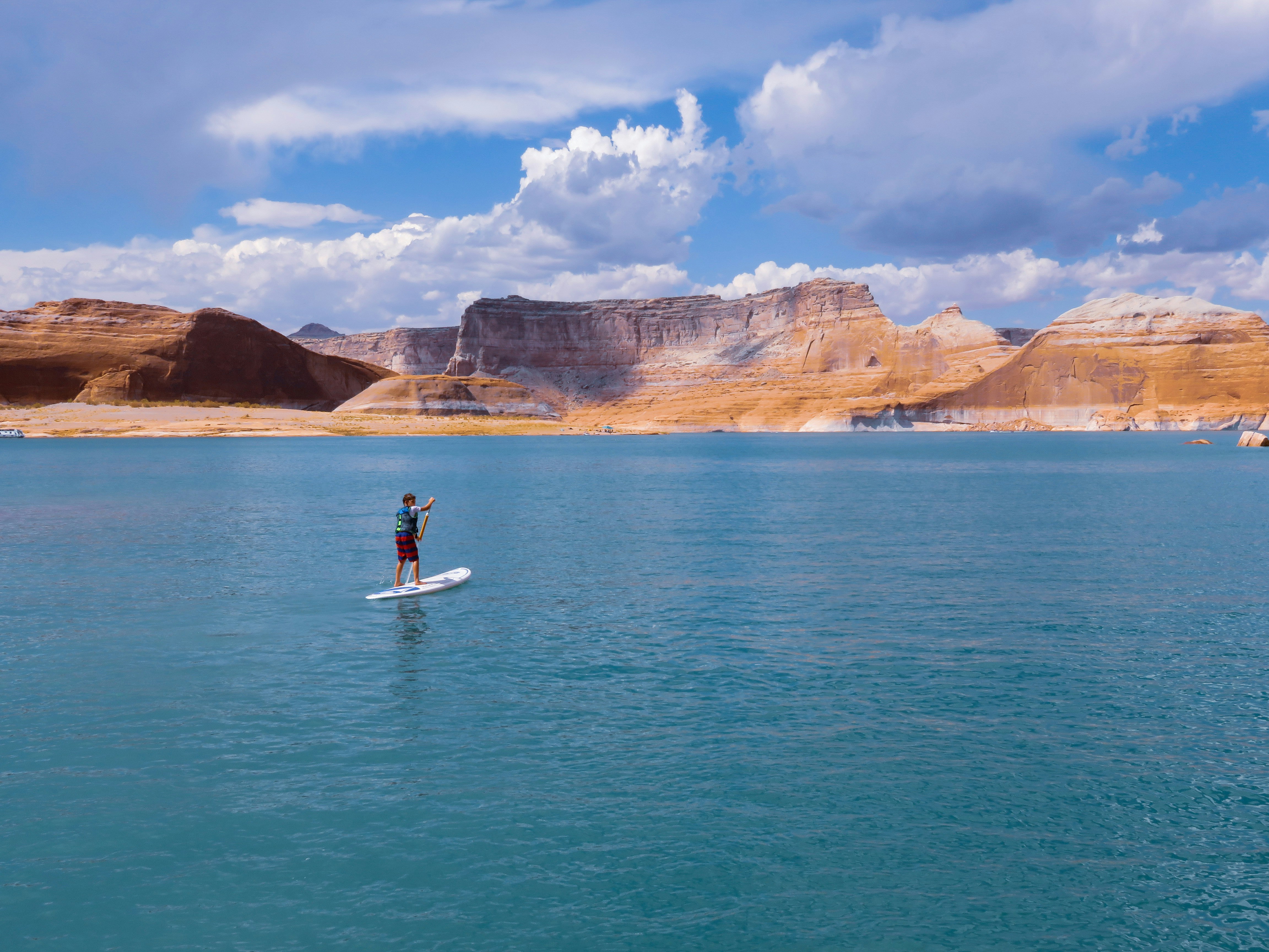 man standing on surfboard under white and blue clouds