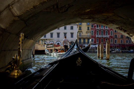 A gondola gliding under a stone bridge in Venice at sunset.