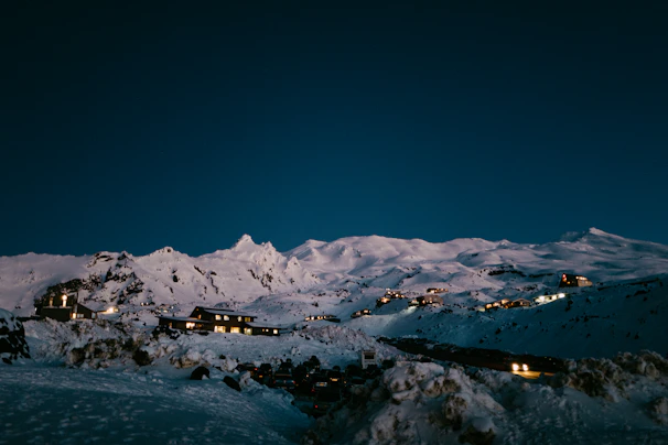 Evening view of a chalet glowing warmly against a backdrop of twilight mountains.