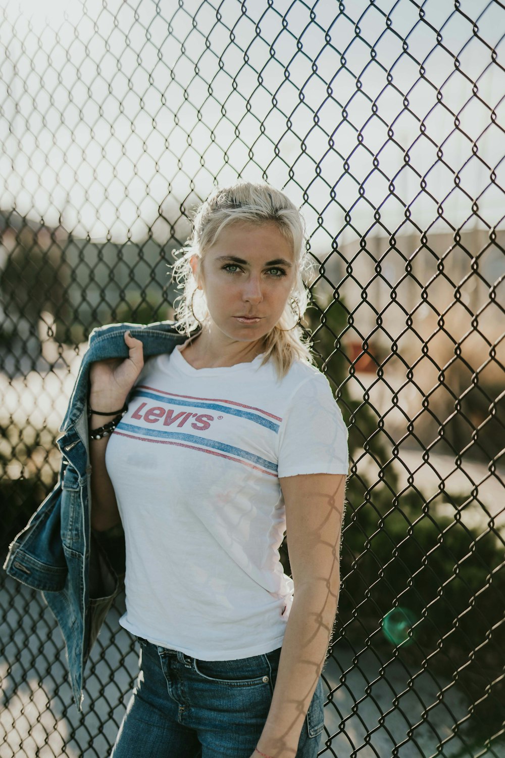 woman standing beside chain link fence during daytime