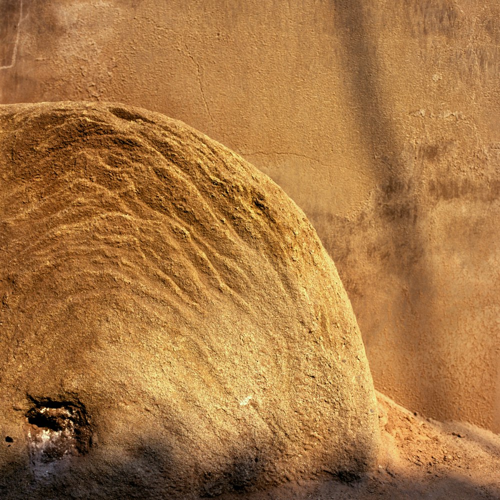 a large rock sitting next to a wall