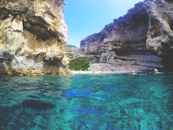 Crystal-clear turquoise waters of Wadi Shab surrounded by rugged cliffs and lush greenery.