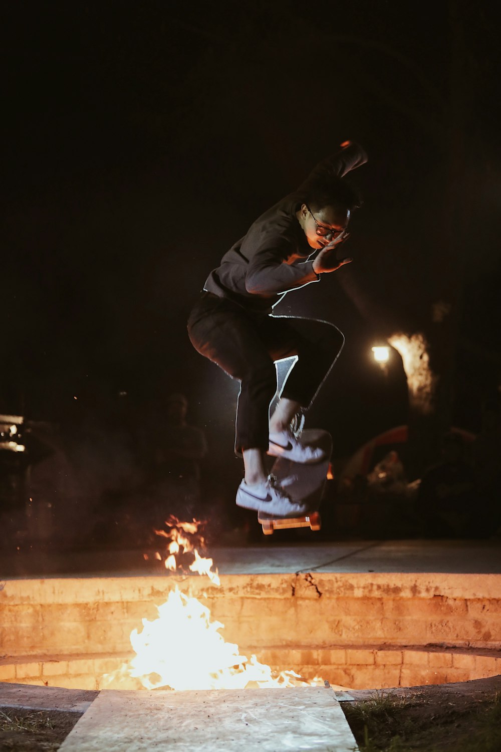 검은 재킷을 입은 남자가 불 근처에서 스케이트 보드