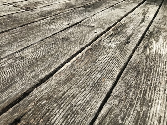 Weathered wooden planks with visible grain and texture extending diagonally across the frame, showcasing signs of aging and exposure.