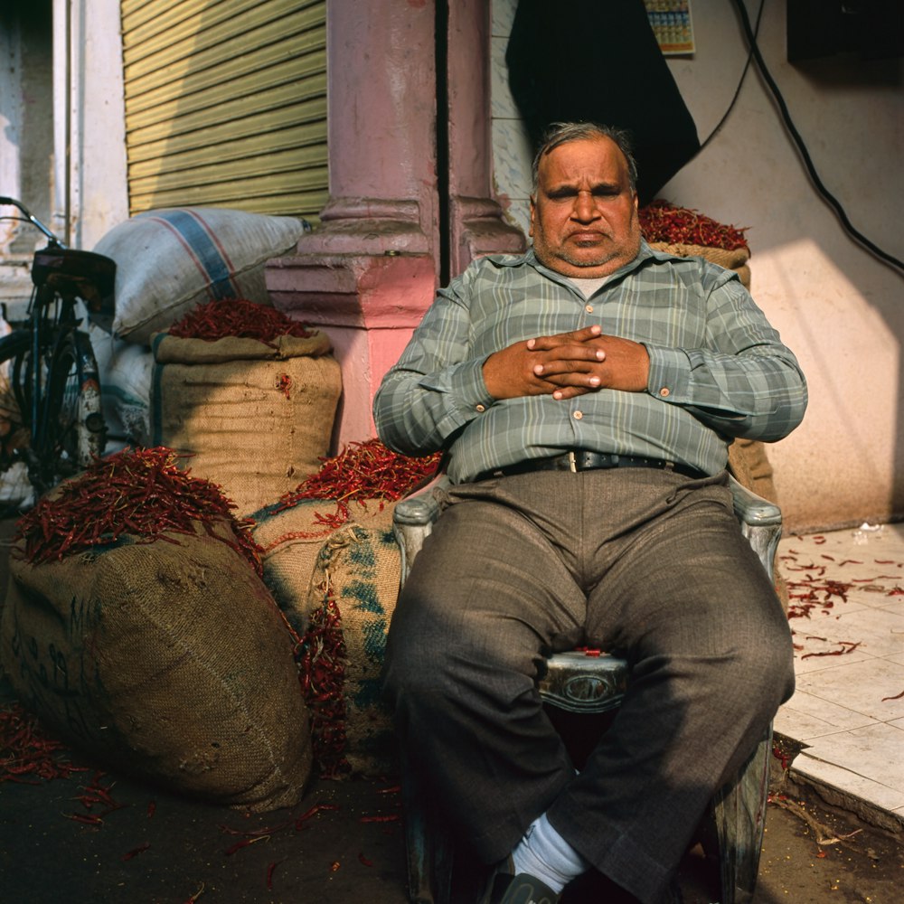 man in grey shirt sitting on chair outside house