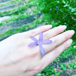 Hands with freshly manicured nails in pastel lilac shades holding a delicate flower.