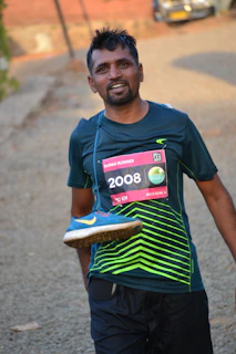 Bakti crossing a small finish line banner with a big smile after a local triathlon event