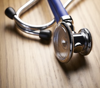 shallow focus photo of blue and gray stethoscope on brown wooden table