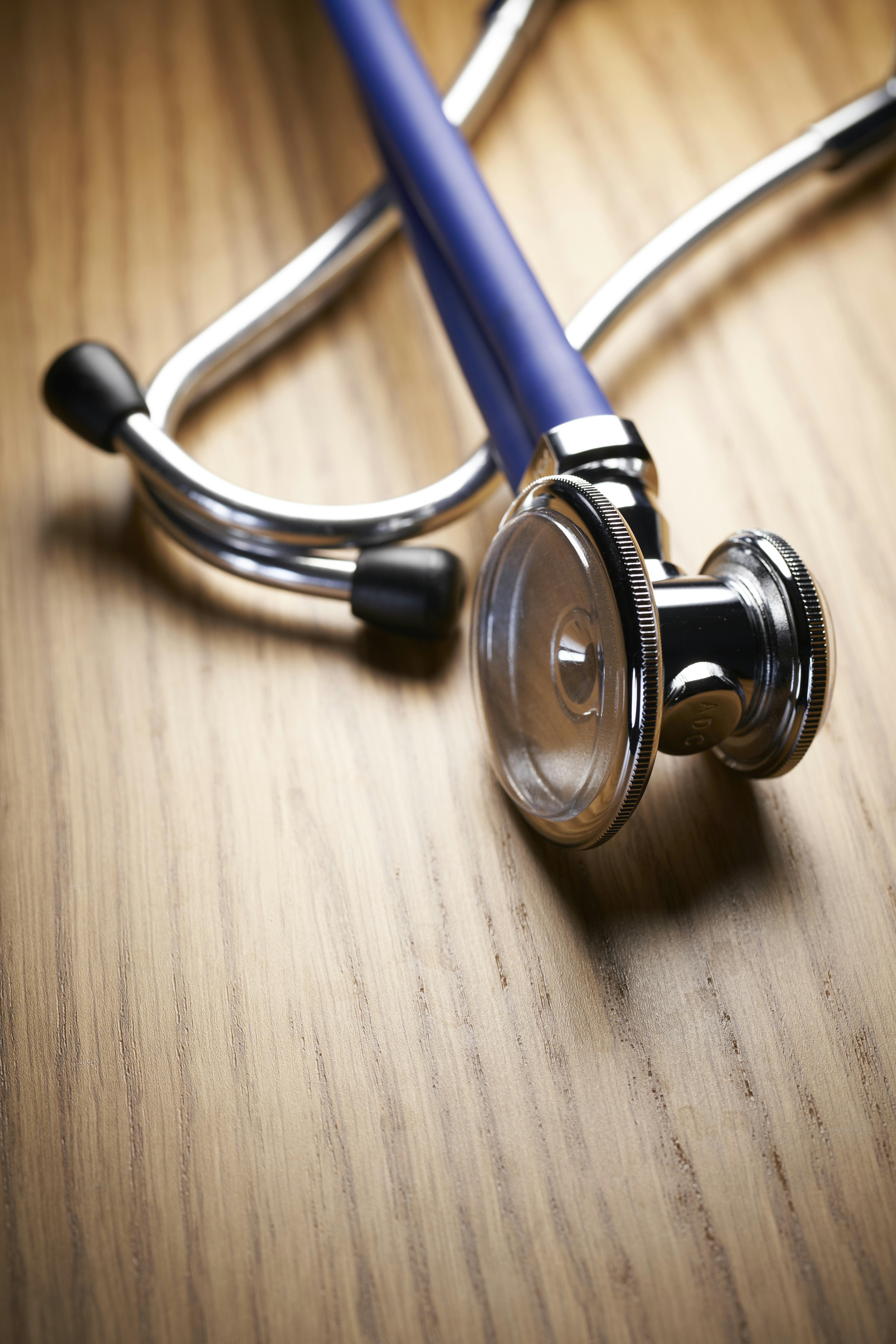 shallow focus photo of blue and gray stethoscope on brown wooden table