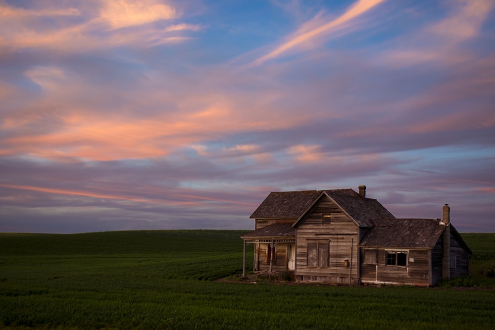 brown wooden house near green grass field during daytime