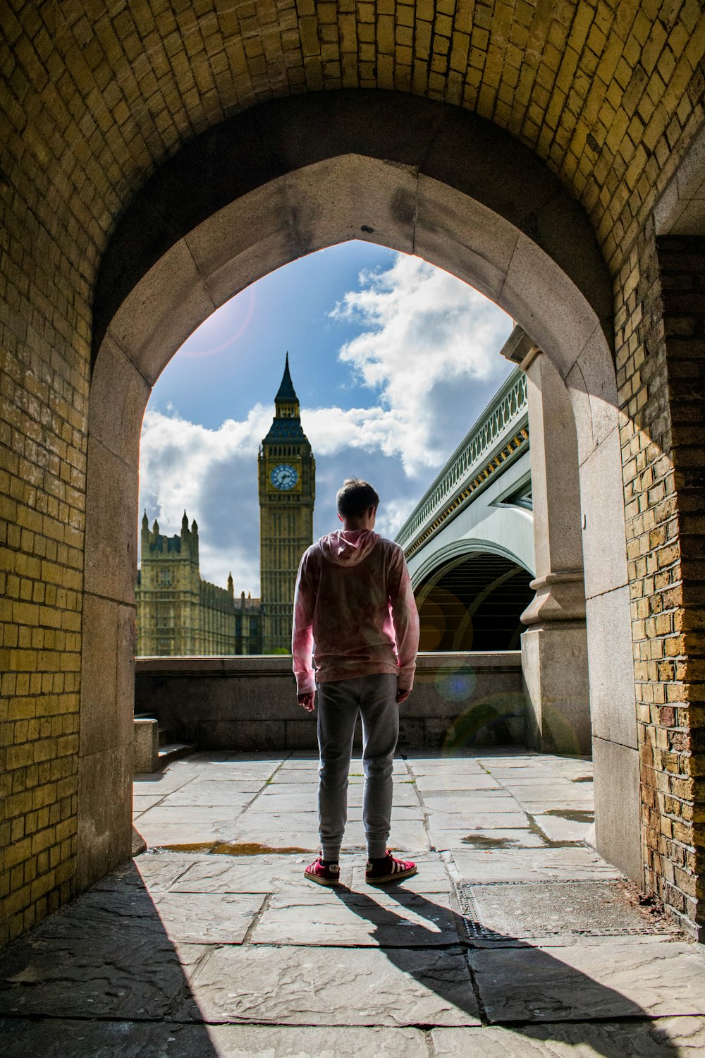 man standing on arch bridge