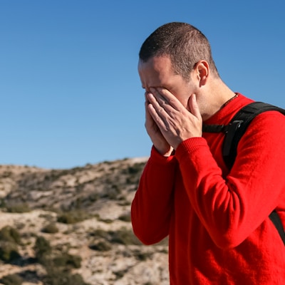 man wearing red crew-neck sweater with teal and black backpack outdoor during daytime