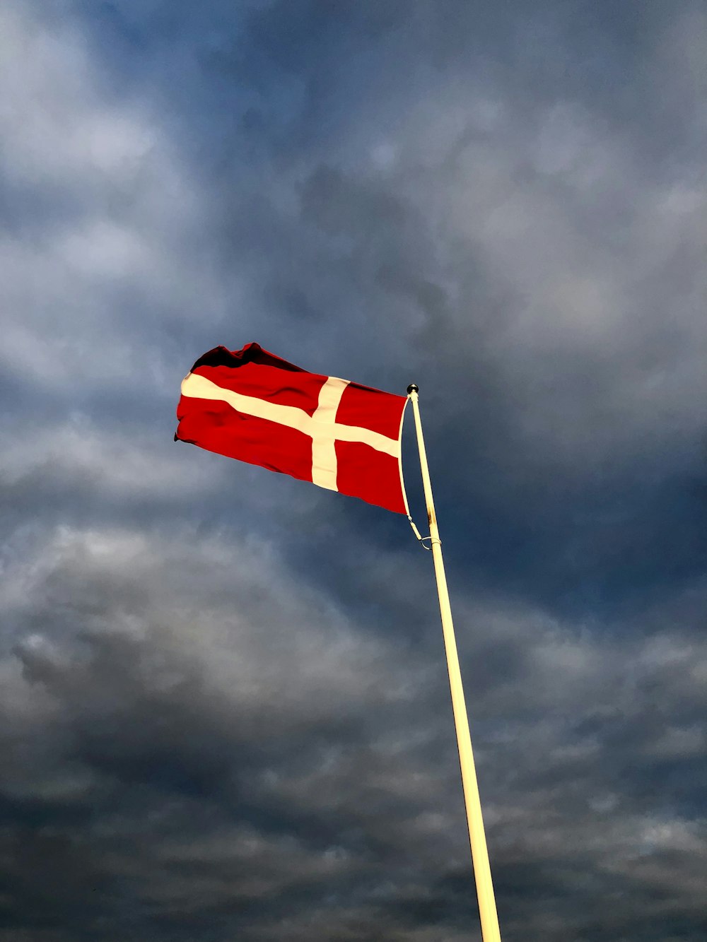 red and white cross flag on top of pole during day