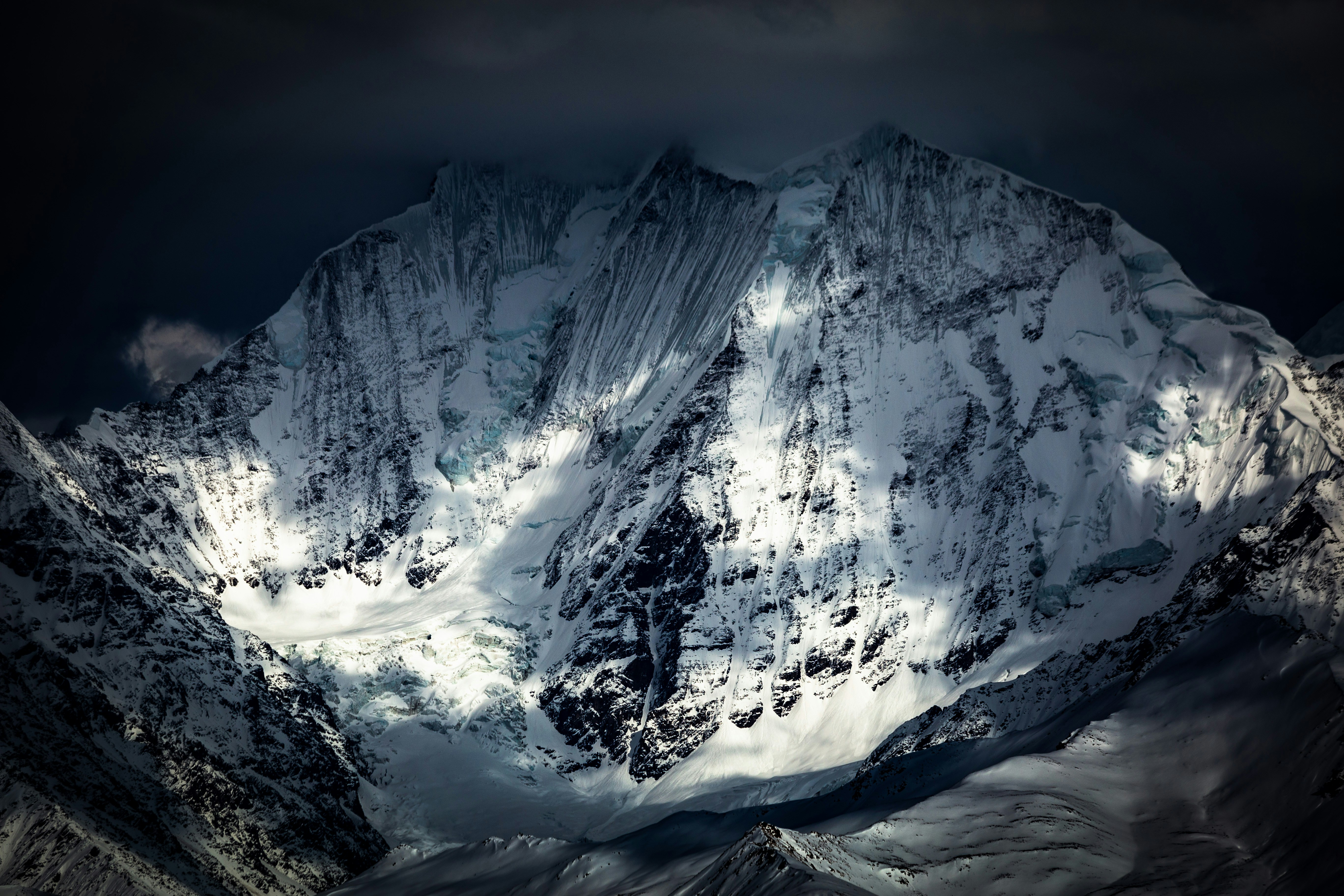 a large mountain covered in snow under a cloudy sky
