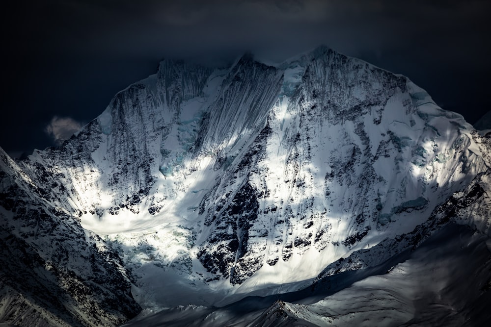 a large mountain covered in snow under a cloudy sky