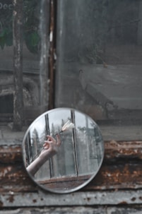 round leaner mirror with reflection of woman holding white flower