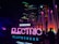 An outdoor night scene features a vibrant and illuminated sign reading 'Samsung Electric Playground' in neon colors. The background includes modern buildings and numerous tall, colorful light installations. A few people are visible, and the atmosphere is lively with bright, colorful lights dominating the setting.