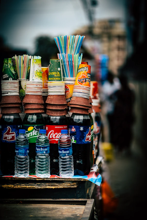 Selection of drinks including a small cola bottle, tetra pack lassi, and mineral water bottle.